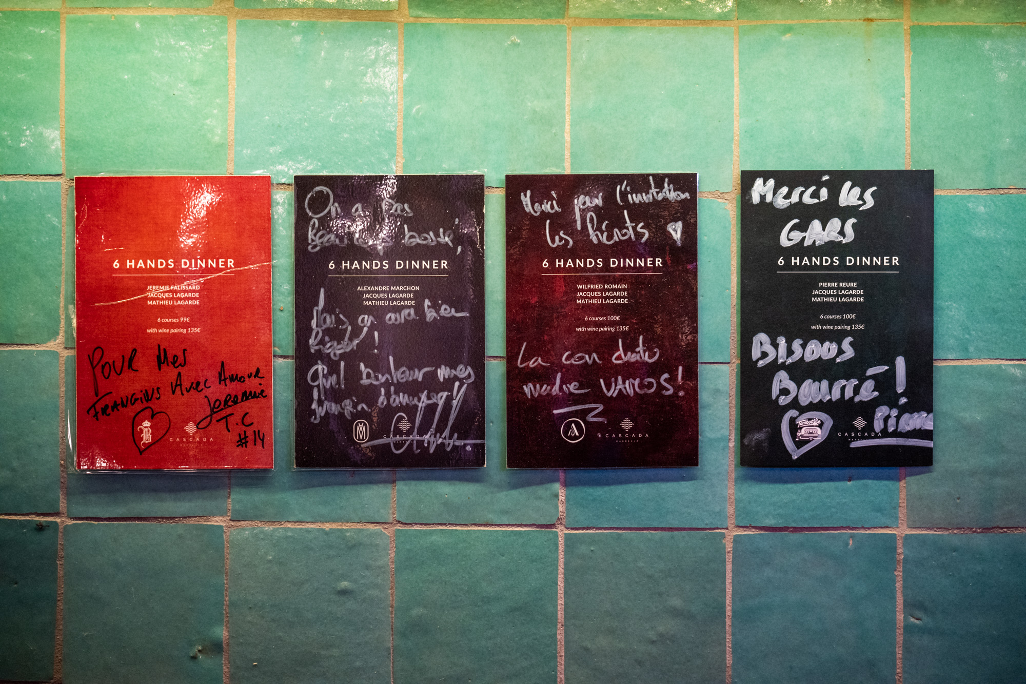 Four signed 6 Hands dinner menus mounted on Cascada's green tiled wall